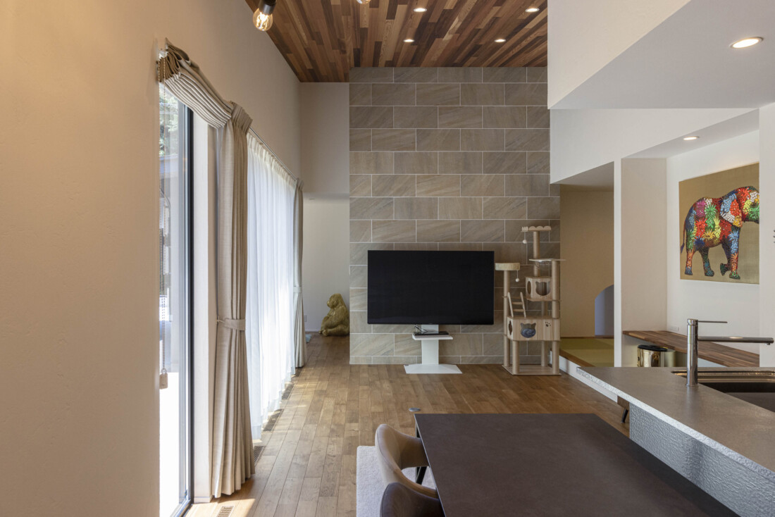 チェックハウス｜大画面テレビが配置されたリビングダイニングスペース。明るい光が差し込み、開放感がある。