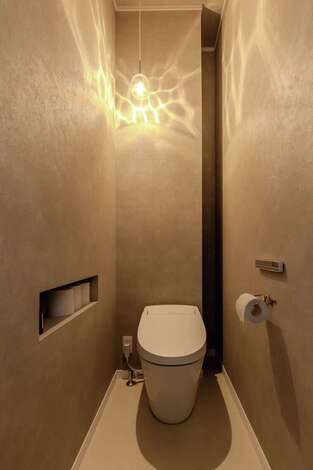 1階のトイレは来客も使うため、トイレットペーパー用のニッチや、奥の壁裏に作った収納スペースなど技あり設計が光る。シンプルながら洗練された印象なのは、あえて壁紙を1色で統一し、照明で景色を作っているから