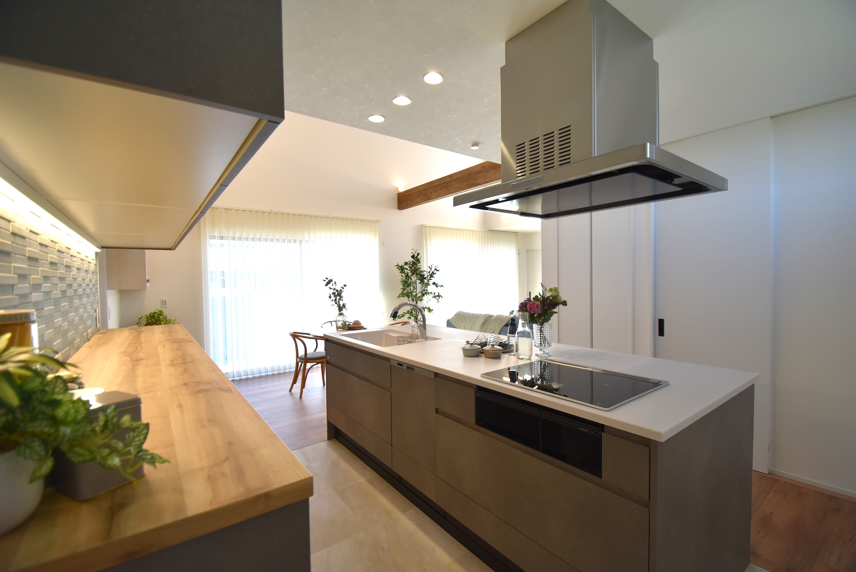 カクニシビルダー｜木目柄の天板をあしらった特注の背面収納と北欧カラーのタイルが、よりスタイリッシュさを際立たせている。