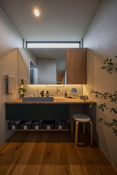 背面に波型のガルバリウムをあしらった洗面。間接照明がその波の表情をより引き立てている。 アイアンバーは歯磨き粉や化粧品を吊るすのに便利。 ミラーとカウンターの高さは、ドレッサーとしても使用できるように設定した。