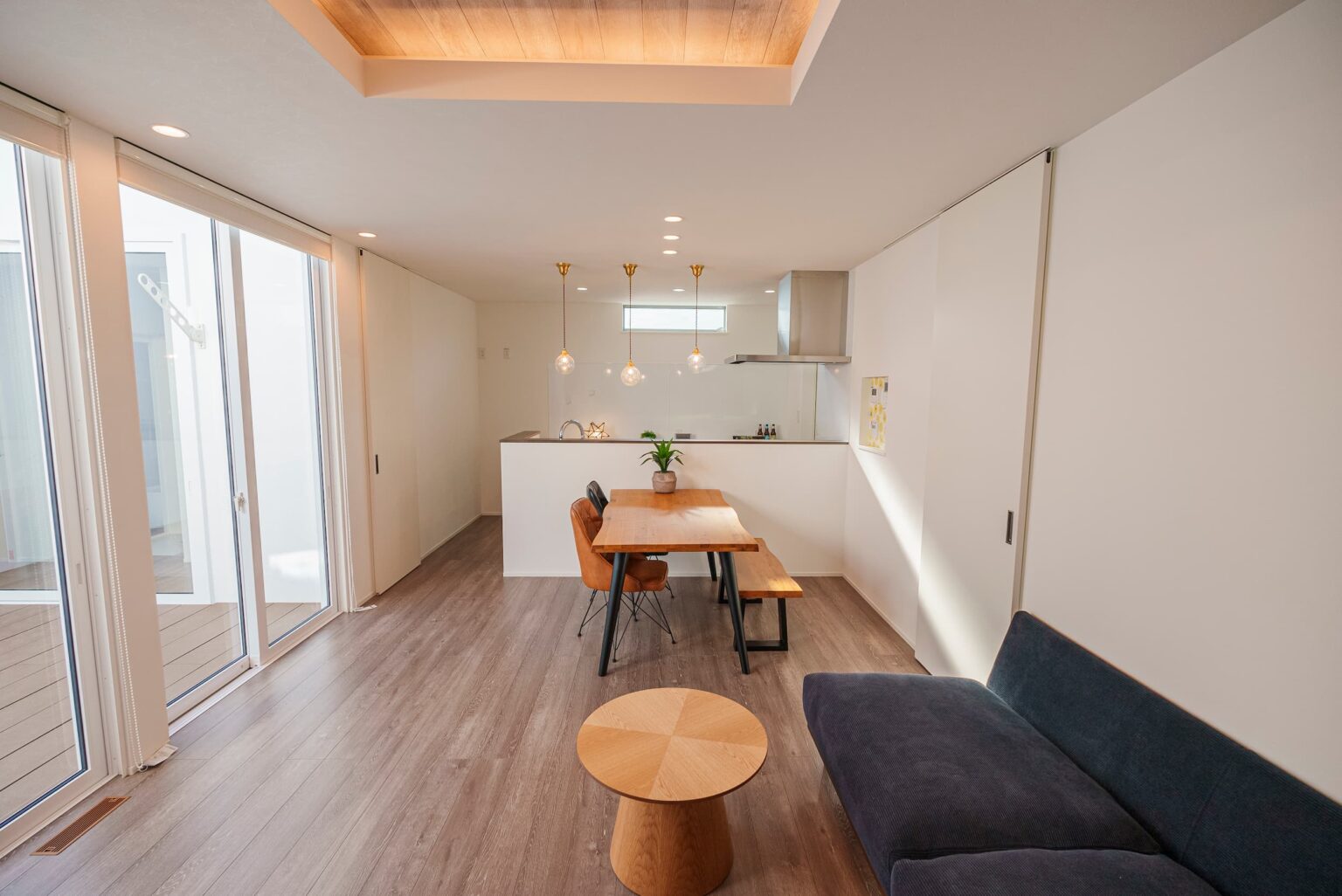 Touch House（タッチハウス）【子育て、間取り、平屋】リビングの一部を折り上げ天井にして間接照明を取り入れることで、白で統一したシンプルな空間にさりげなくアクセントが加えられた。中庭に面した窓はハイサッシに。隣室へと続くドアもハイドアにすることで、空間が広く感じられる