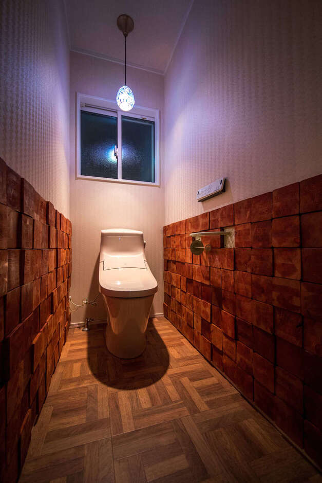1階のトイレ。大工さんに分けてもらった柱材の余りをご主人がカットして壁に貼り、個性ゆたかな空間が実現