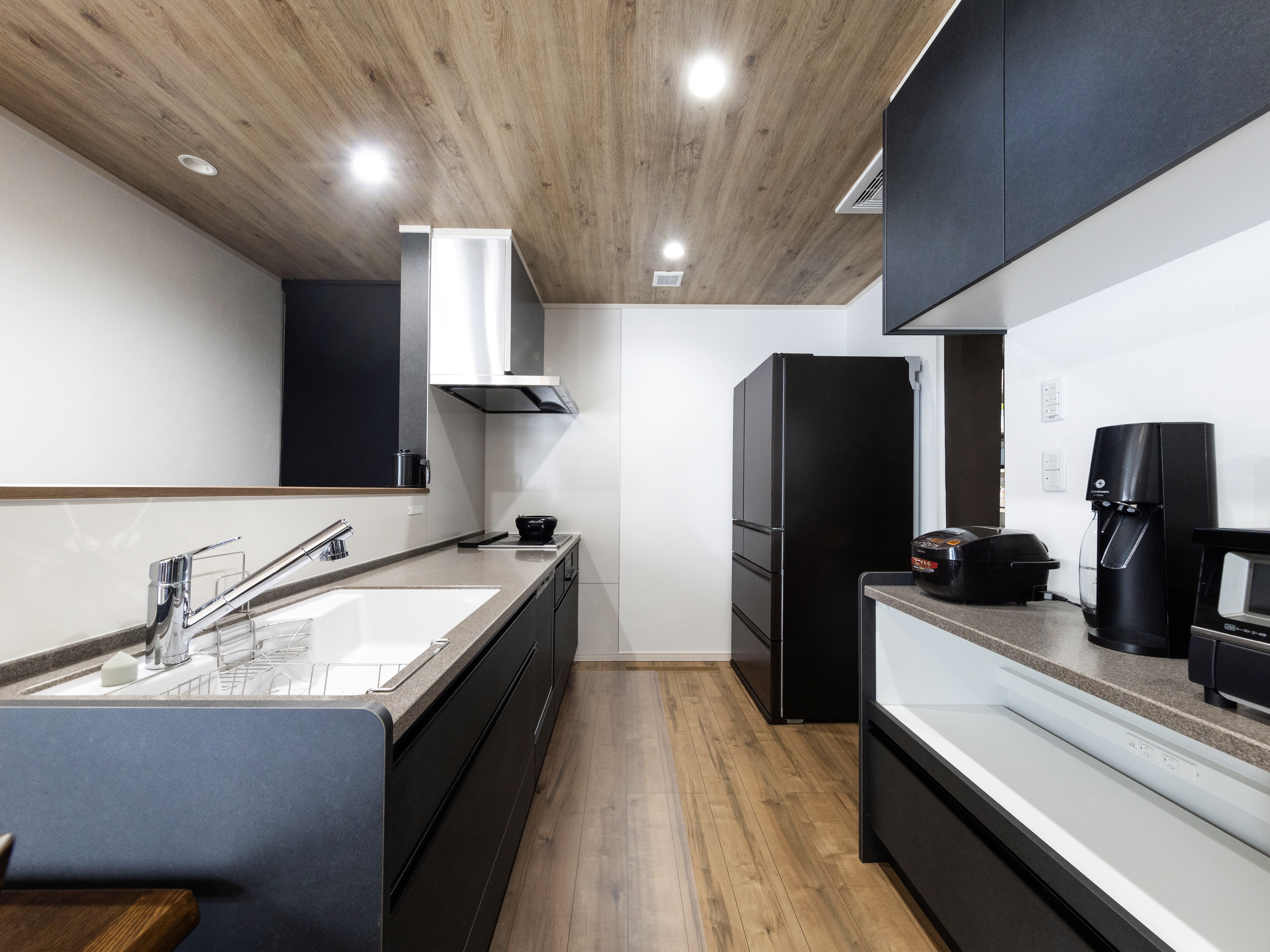 エスホーム｜木目調の天井とシンプルなデザインが特徴のキッチンで、広々とした作業スペースが確保されている。収納力も十分で機能的。