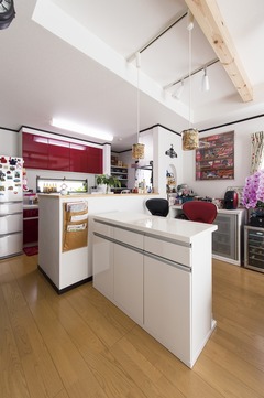 明るいライトと赤のアクセントが効いたキッチン。カウンターが付いており、料理と同時に作業スペースとしても利用可能