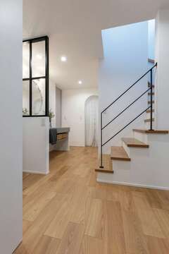 玄関ホールは、階段の壁をアイアン手すりにして空間のアクセントに。水回りやパントリーへの動線上にある洗面台も袖壁の上部にガラスの格子窓を取り付け、明るくおしゃれな空間に整えた