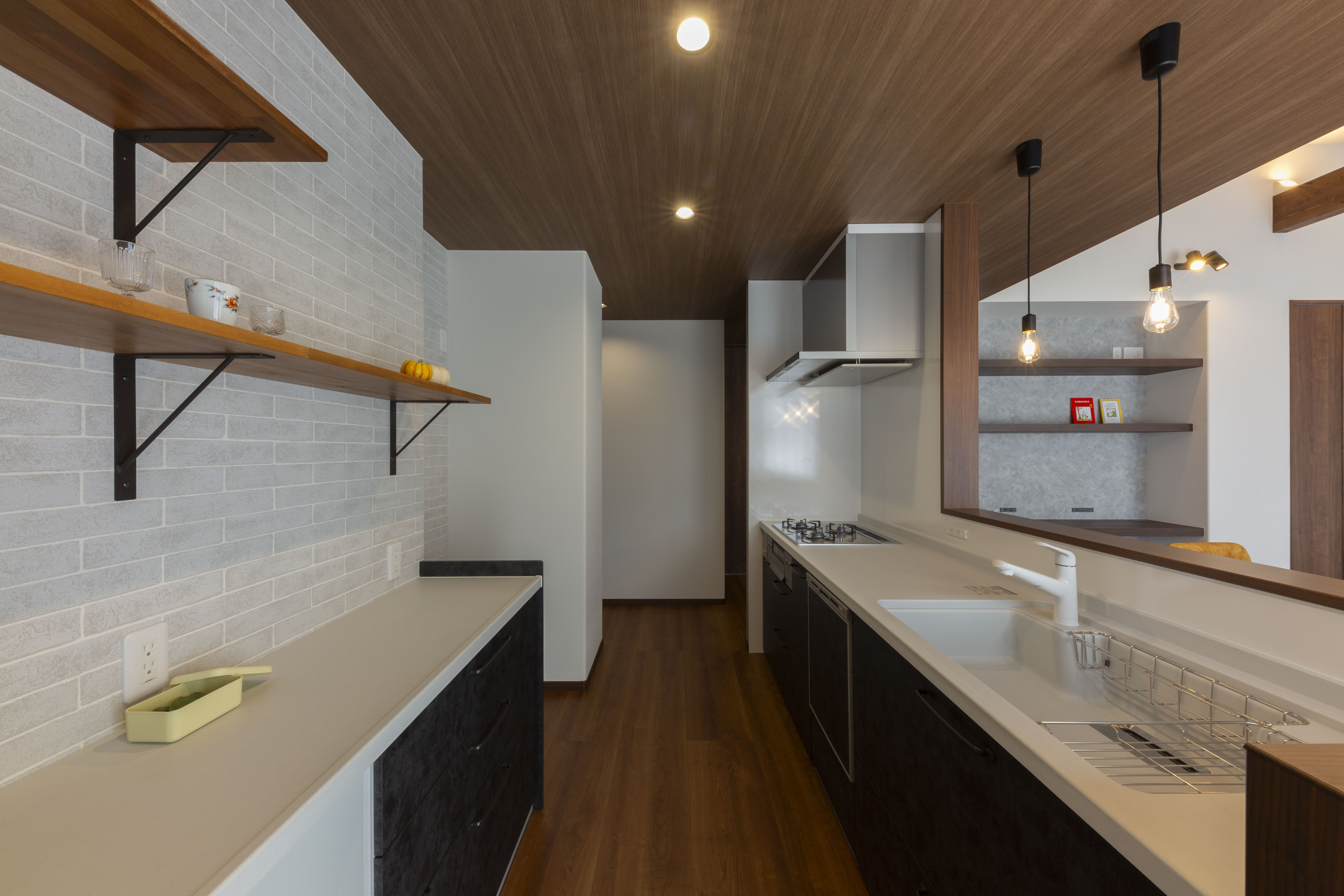 感動ハウス｜下がり天井がアクセントのモダンなキッチン。シンクとコンロが互いに並び、作業効率がよい設計。オープンシェルフが便利でスタイリッシュな空間を演出している。