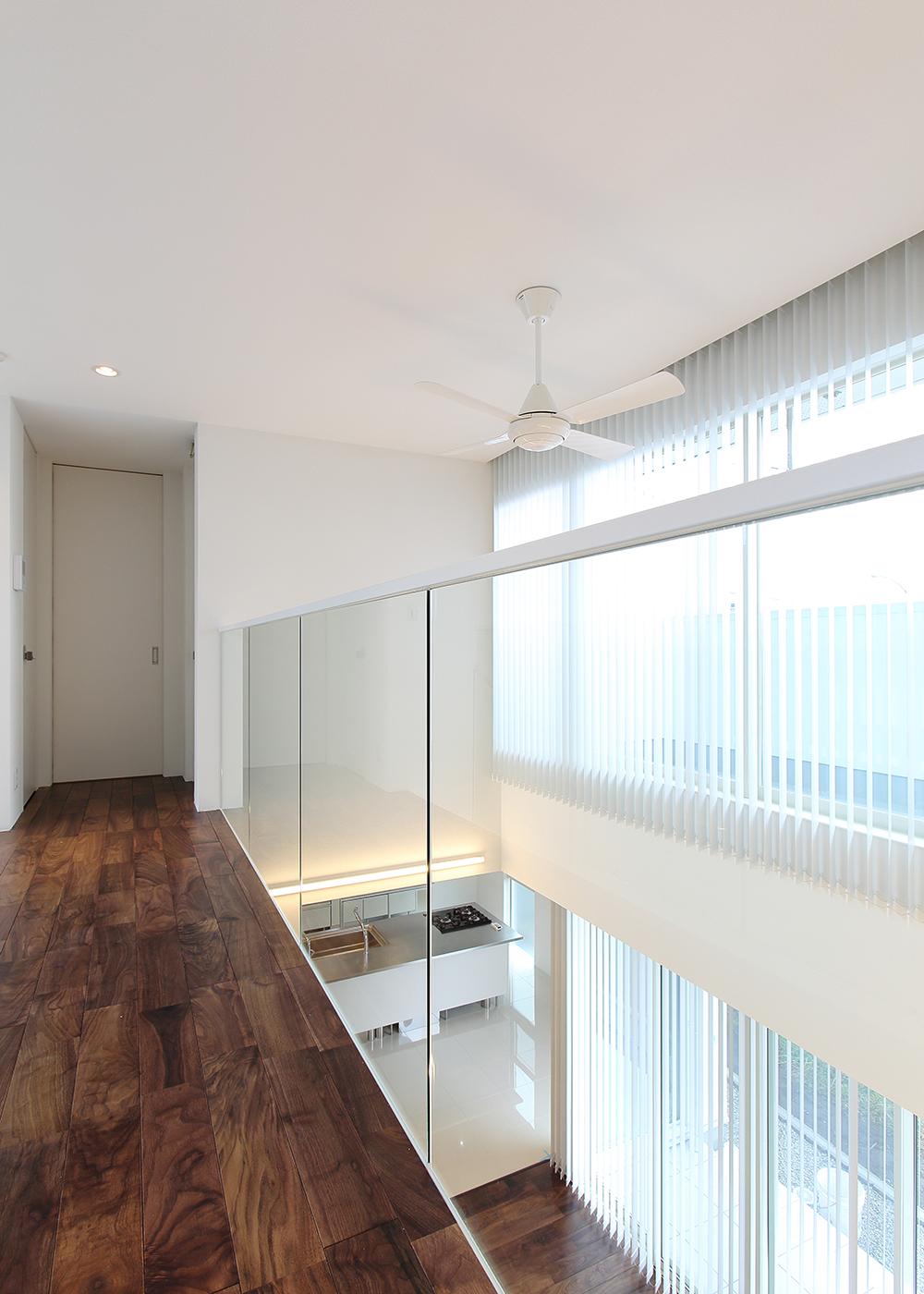 丸昇彦坂建設【デザイン住宅、間取り、ガレージ】2階を繋ぐ渡り廊下は開放的な吹抜けともに、スケルトンの手摺、南面いっぱいに取り付けられたバーチカルブラインドによって非日常的なデザイン