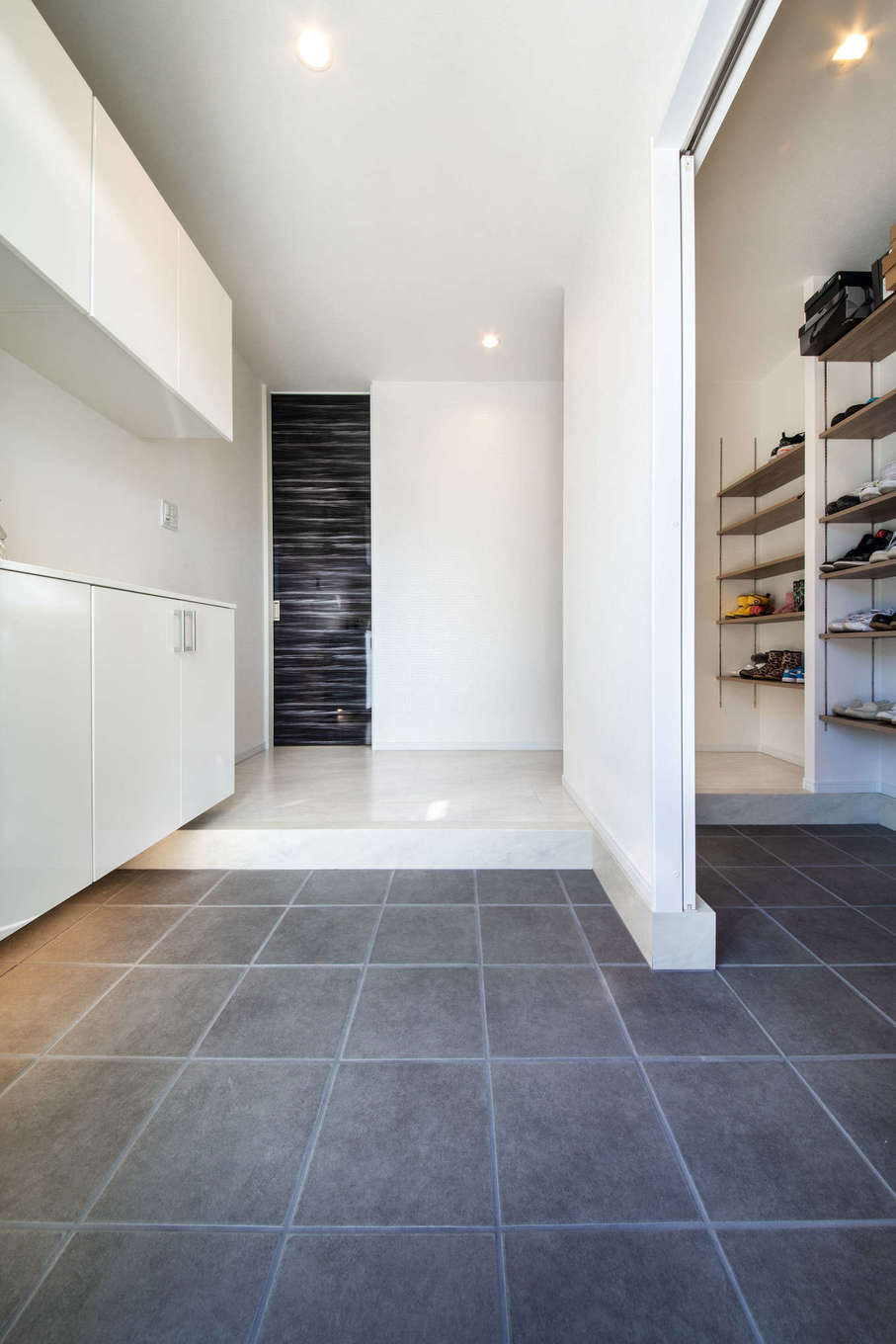 吉川住建【子育て、省エネ、ガレージ】白で統一した玄関は、大容量のシューズクローク付き。正面のハイドアは黒の鏡面仕上げで高さは2,500mm