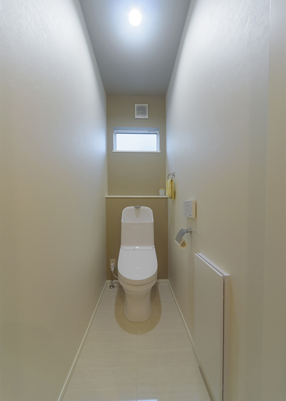 KAZA DESIGN【間取り、屋上バルコニー、インテリア】1階のトイレの床にも光沢感のあるタイルを採用。タイル敷きは玄関から続いていて見切り材もないので、掃除もスムーズ