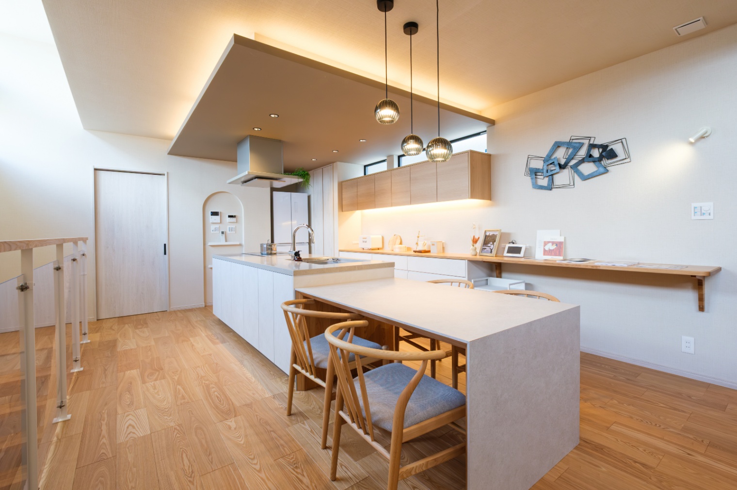 新栄建設｜キッチンと統一感のあるダイニングテーブル。折り下げ天井とおしゃれな照明が、食事の時間を楽しくする空間を演出している。