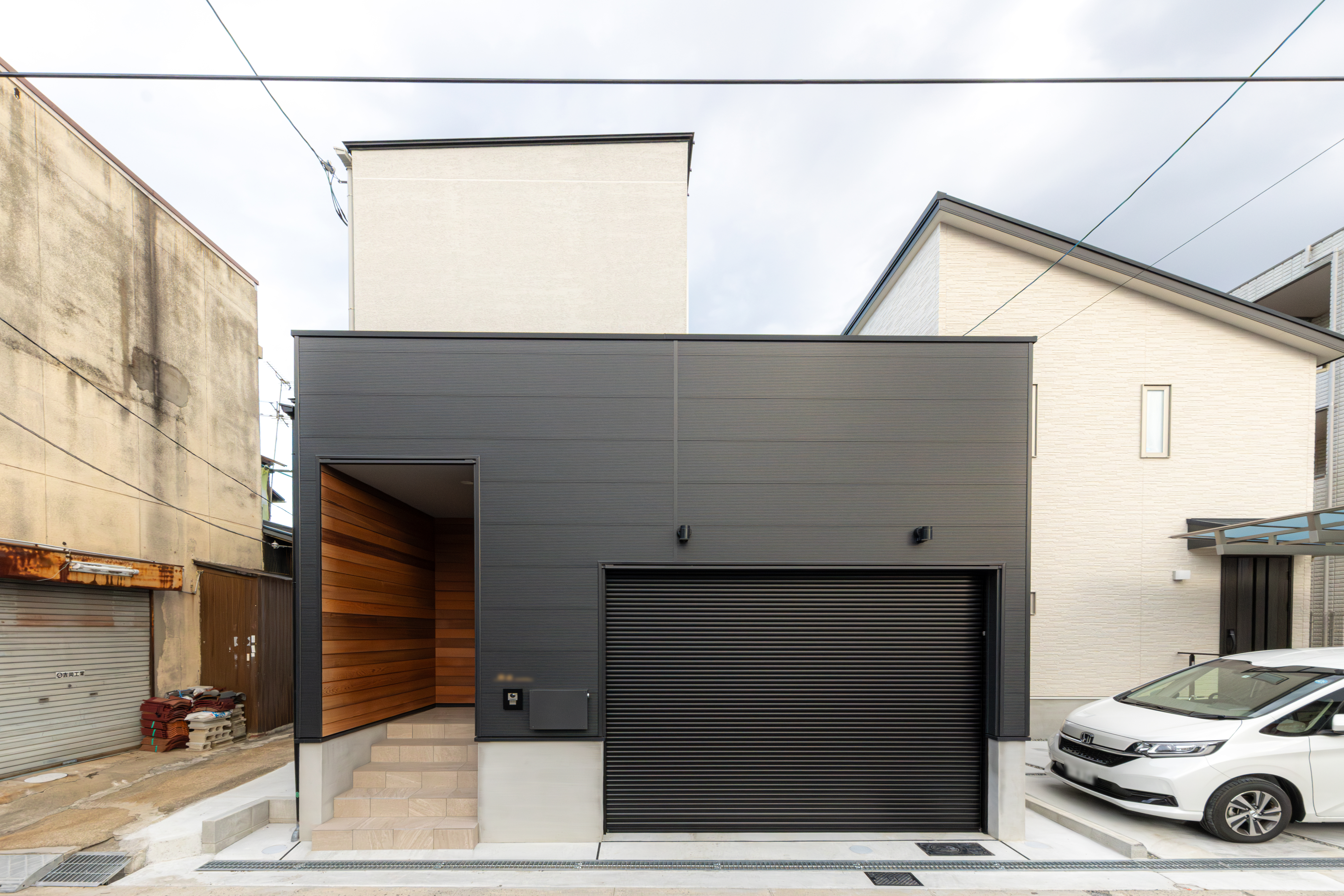 しんやま工務店｜モダンなデザインの戸建て住宅の外観。シンプルなラインと色合いがスタイリッシュな印象を与える。黒いガレージドアがアクセントになっている。
