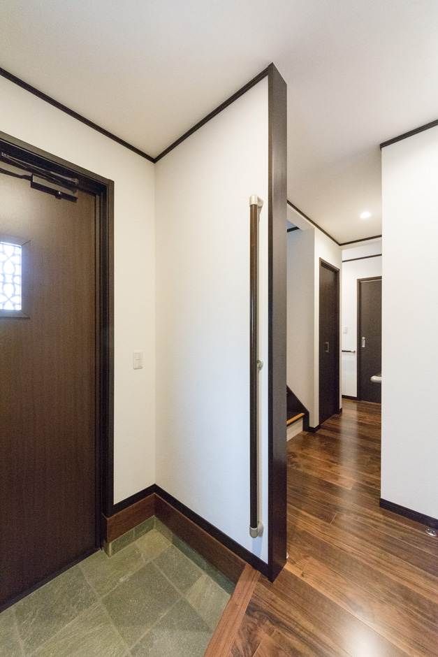 イーホーム【収納力、二世帯住宅、屋上バルコニー】石畳とウォールナットの床が落ち着いた雰囲気を醸し出している玄関。長めに設置した昇降用の手すりはお子さんからご年配まで安全に使用できる