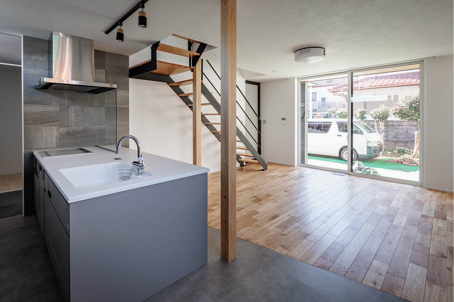 tact design firm【デザイン住宅、子育て、間取り】広々としたリビングダイニングキッチン。開放感のある窓と階段があり、家族が集える心地よい空間となっている