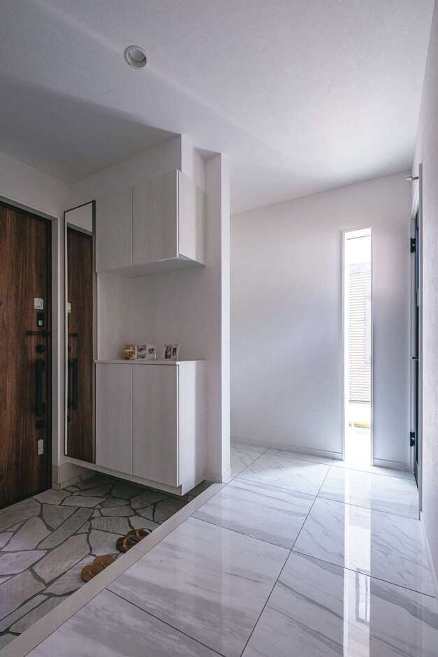 白でまとめた玄関はリゾートホテルのような仕上がり。スリット窓から光を取り入れて明るさも確保した