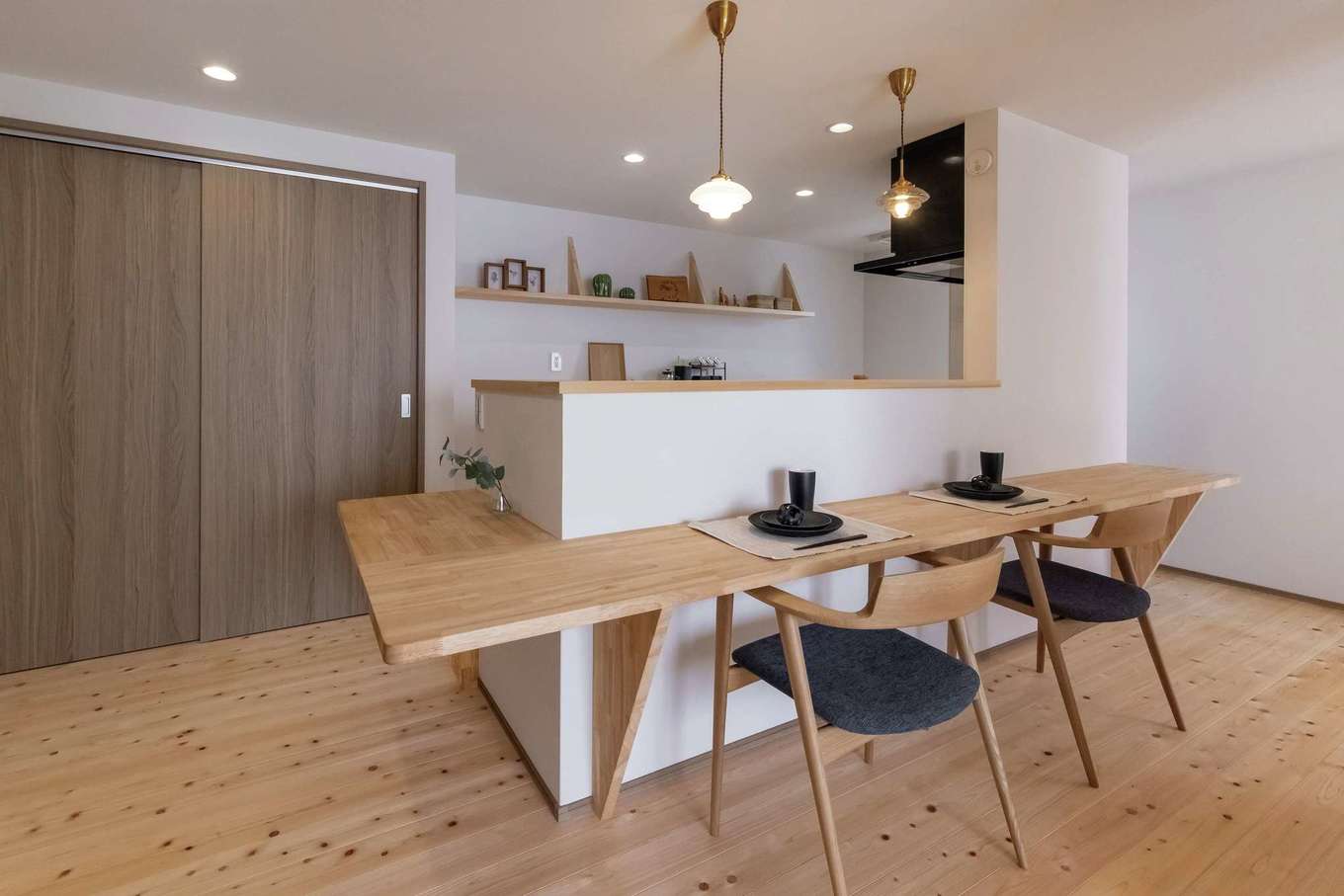 住まいるコーポレーション｜元和食料理人のご主人がリタイア後、自宅でカフェを開きたいという夢に向けて、最初からカウンター一体型のオープンキッチンを造作。ここで家族4人で食事をとっている。昭和レトロなペンダントライトは施主支給