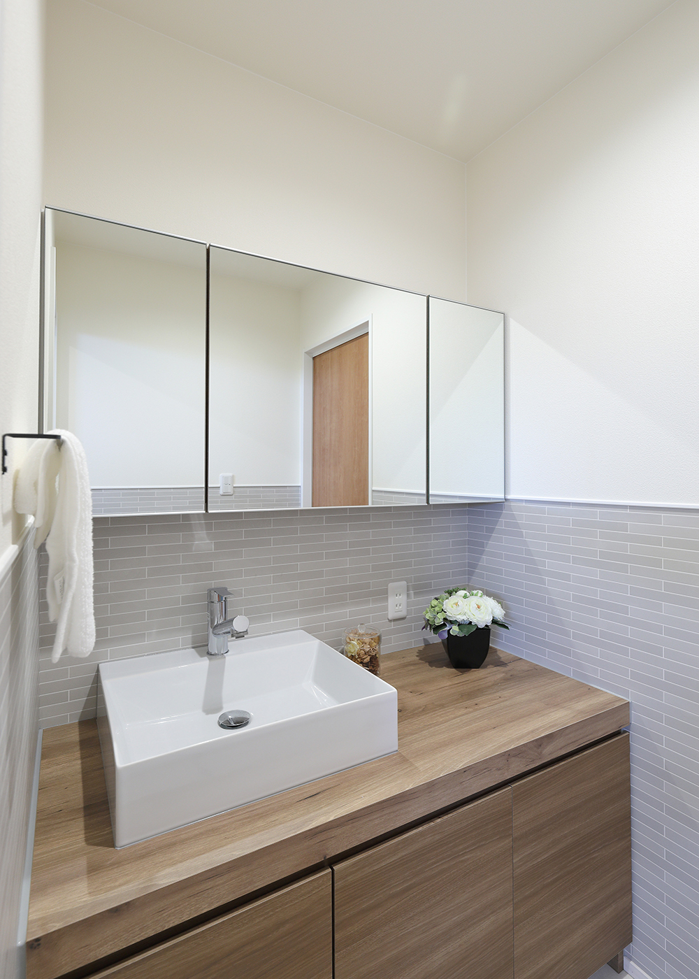 丸昇彦坂建設【子育て、収納力、間取り】造作の洗面台は、カウンター下に加えて、鏡の裏面も収納になっている。玄関ホールから入ってランドリーに通り抜けられる、便利な動線を確保