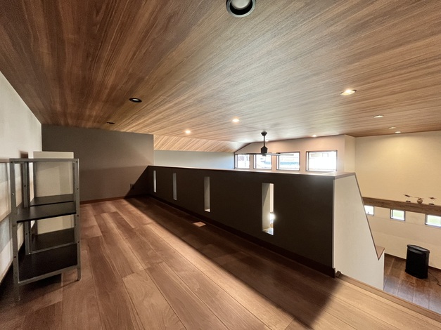 天井が低めのロフトスペース。落ち着いた色合いの木材を使い、くつろげる空間を演出している。窓から自然光が差し込み明るい。