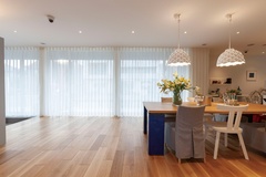 明るい自然光が降り注ぐ玄関ホールからダイニング空間。大きなテーブルとゆったりした椅子が並び、開放的で落ち着いた雰囲気を作り出している。