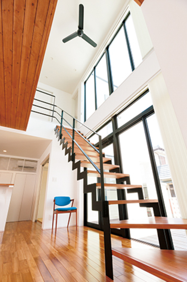人通りの激しい南面の窓を小さくした代わりに、東面に大きな鉄骨サッシを設けて採光と通風を確保。白い漆喰と黒いオープン階段のコントラストが素敵