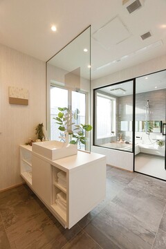 広々とした明るい洗面スペース。ガラス仕切りでバスルームと視覚的につながり、洗練されたデザインが特徴です。