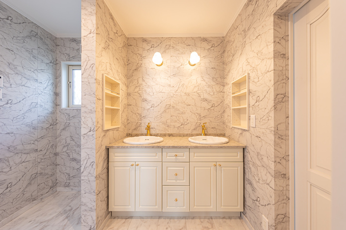 高級感あふれるダブルシンクの洗面スペース。大理石を思わせる壁がモダンな雰囲気を演出しており、明るい照明が空間全体を柔らかく照らしている。