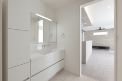 白を基調とした清潔感あふれる洗面スペース。広い鏡と収納が備わっており、使いやすさを重視した設計となっている。