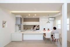 同社の造作による一体型のカウンターとダイニングテーブルの回りに自然に家族が集まる。間接照明が施された折り下げ天井にはじまり、収納や窓のセレクト、絶妙なカラー選びと配色、さらにはペンダントライトや椅子などのインテリアまで、トータルでコーディネート。気持ちよく過ごせるDKが完成した