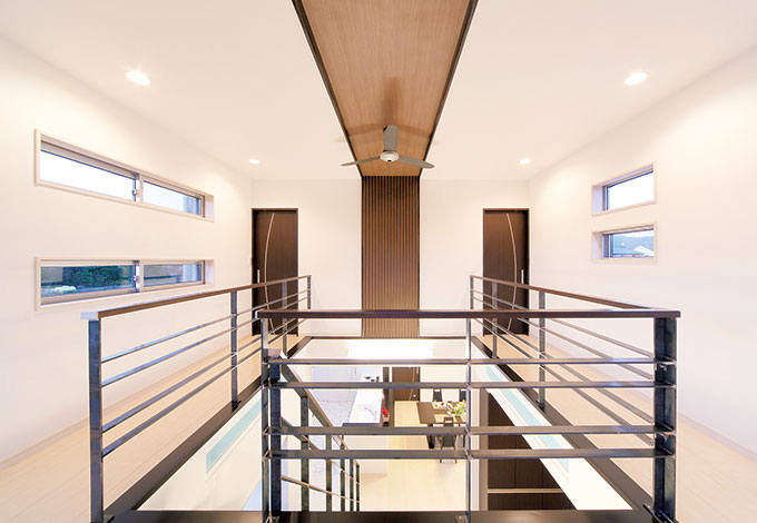 大成工務店【デザイン住宅、二世帯住宅、間取り】吹き抜けの周囲はシンメトリーのデザイン。フラットバーの手すりにすることで、視線の抜けとスッキリ感がもたらされ、さらなる広がりが演出されている。天井から壁面の縦スリットのラインも印象的