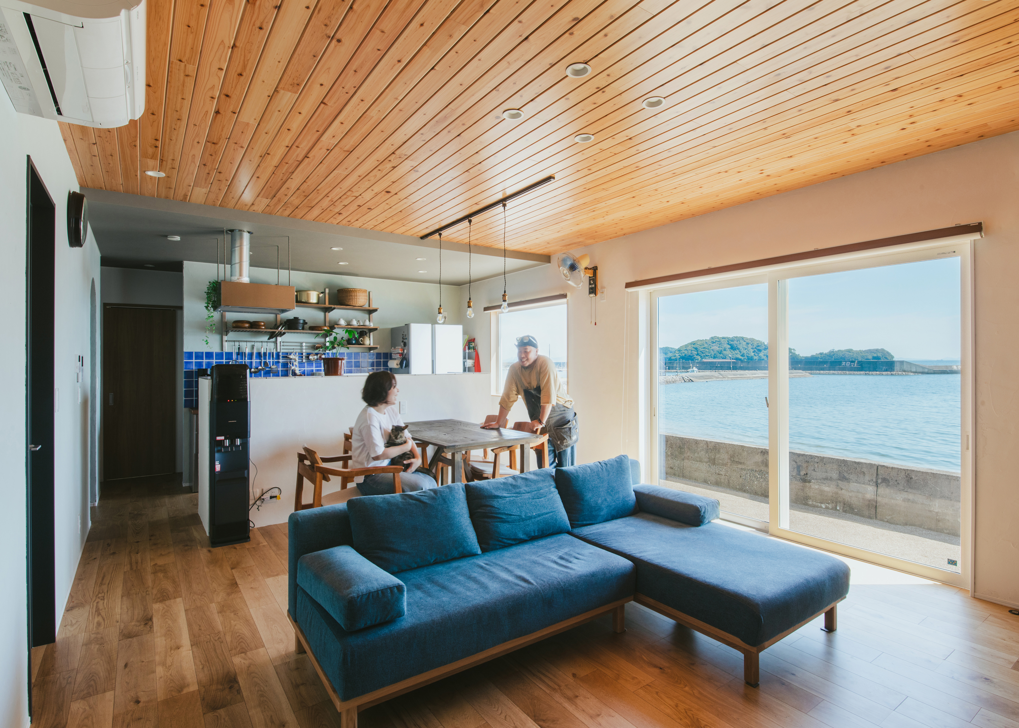 ナイスホーム【デザイン住宅、間取り、平屋】南の大きな窓に三河湾の美しい景色が広がるLDK。天井に杉の羽目板を採用し、空間にやさしさを与える。フローリングは床暖房仕様