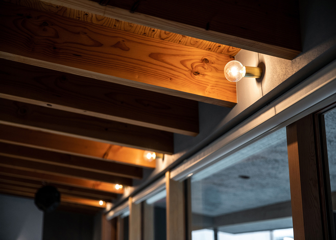 等間隔の太い現し梁と、間接照明の淡い光が空間に落ち着きをもたらす