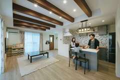 玄関からひとつながりのLDKは、2方向でタイルデッキに面し、さらなる開放感。キッチンに立てば家族を見渡せ、玄関や階段の上り下りの様子も届く。床は無垢フローリング、壁には漆喰を採用