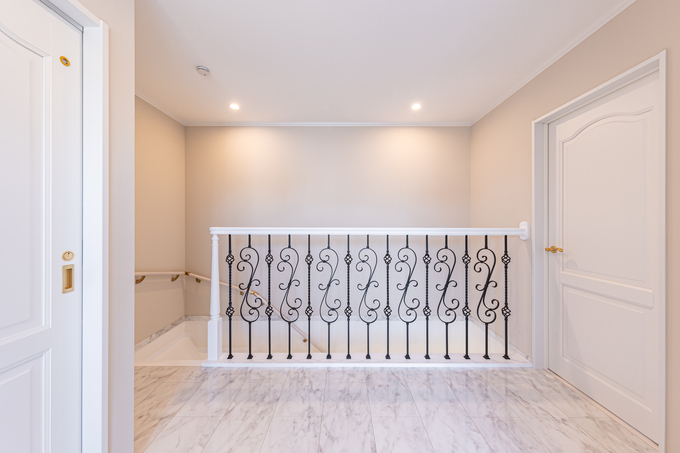 優雅な装飾が施された手すりが印象的な廊下。明るい色調の床と壁が広々とした空間を演出している。