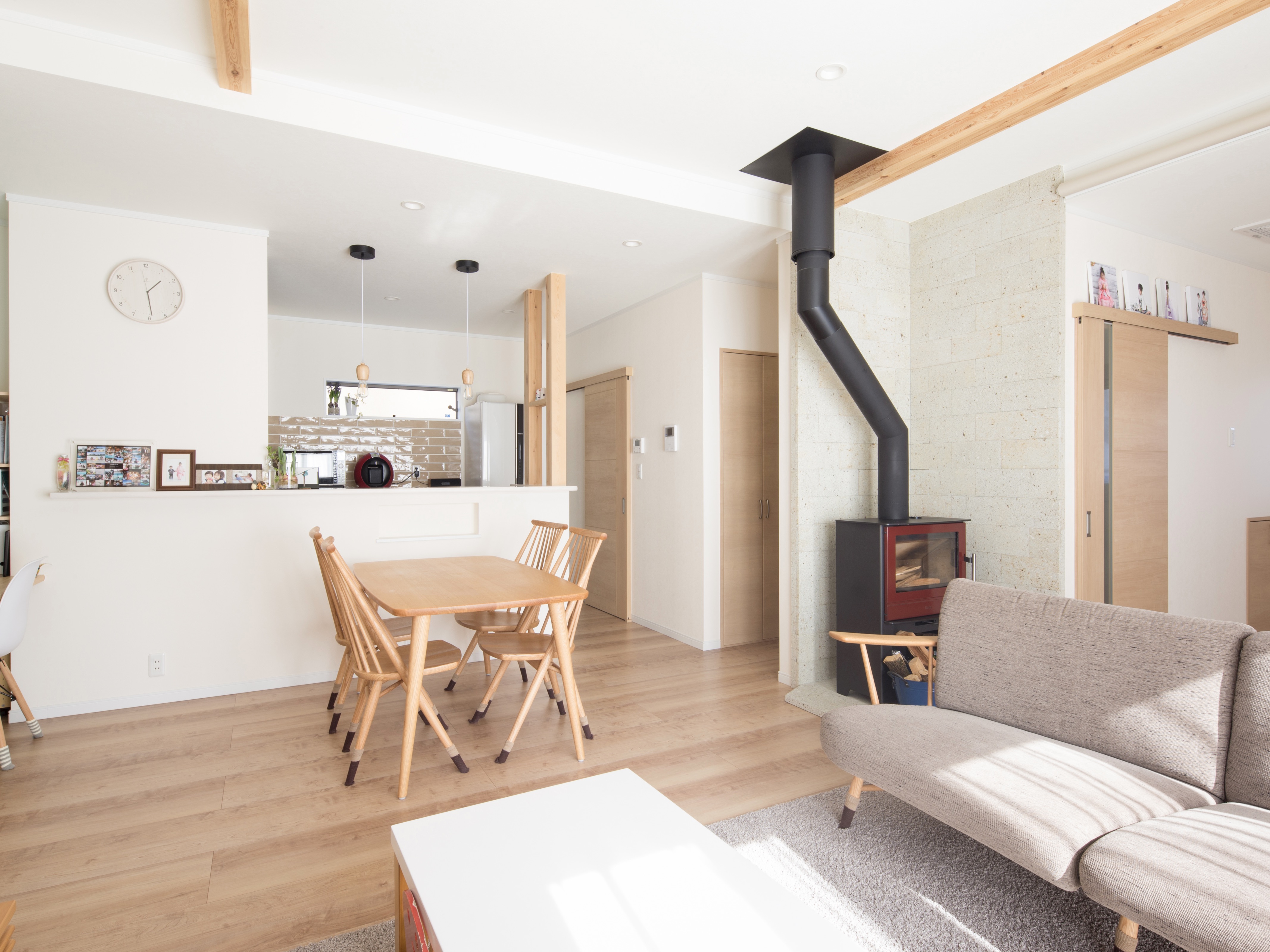 エスホーム｜明るく開放的なリビングダイニングキッチン。薪ストーブがアクセントになり、家族団らんの場としても最適。シンプルなデザインが魅力で、自然光が室内を優しく包み込む。