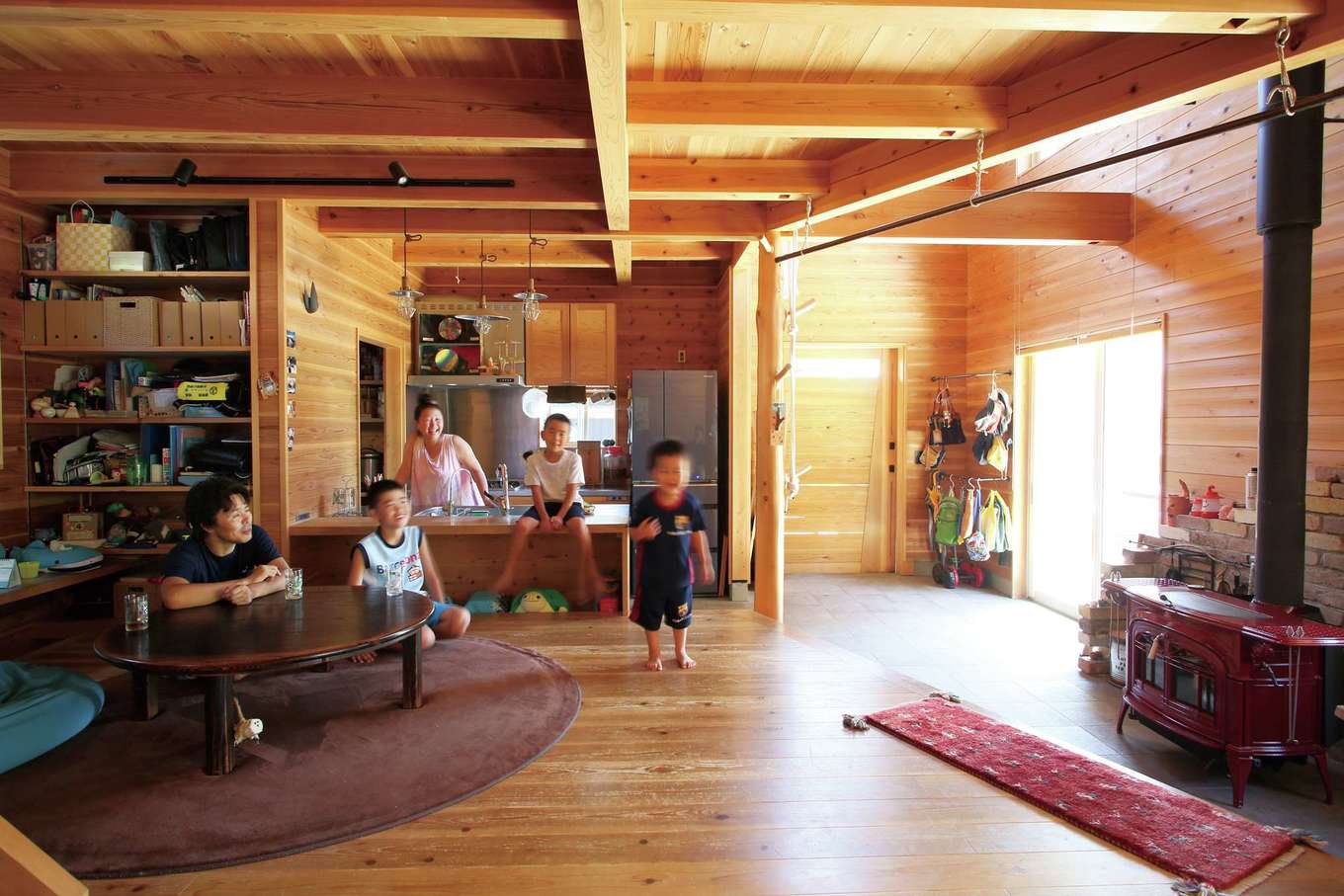 有吉住宅【子育て、趣味、自然素材】玄関、土間、LDKがつながった間仕切りのないフルオープンな空間。築4年が経過し、無垢の柱や床が飴色に変化してきた。冬になると、家族みんなが自然と薪ストーブの前に集まってくる