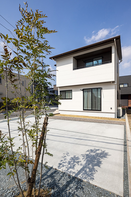 トキワハウス デザイン アンド ビルド（常盤工業）｜シンプルでモダンなデザインの二階建て住宅。庭木がエントランスを彩り、住宅の外観に柔らかさを加えている。