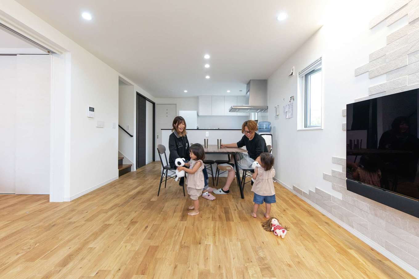 共栄住研【子育て、自然素材、省エネ】ナラ無垢床の足ざわりが心地よいリビングで、子どもたちは年中素足で過ごす。続き間の洋室を仕切る扉は壁の中に収納でき、合わせて22畳の大空間が広がる