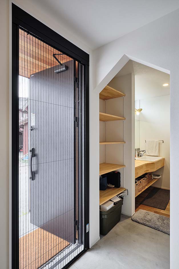 平屋建築ブルーハウス【ペット、建築家、平屋】玄関土間の先は2手に分かれており、一方は洗面がある動線、もう一方は直でリビングへ続く動線となっている。家族が帰宅したら洗面のルートから、ゲストを案内するのはリビングルートでと、状況に応じて2本の動線を使い分けられるため、生活がスムーズに