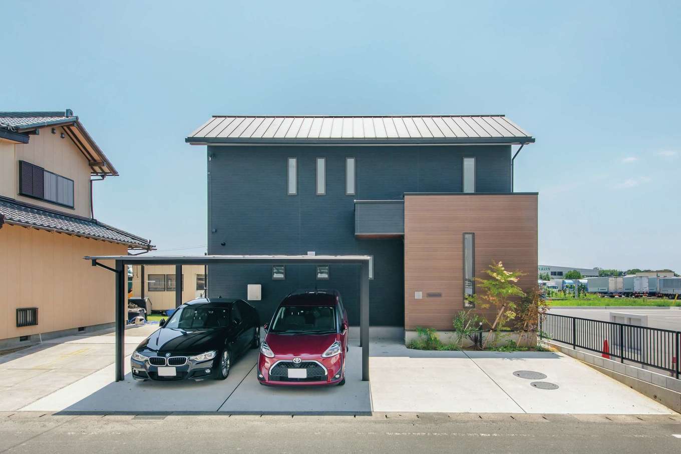 水田建設【自然素材、省エネ、間取り】ダークグレーと木目調の外壁を組み合わせたシンプルな外観。玄関の出入りが道路側から見えないように配慮されている