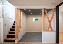 木の柱とシンプルな壁が調和する土間スペース。モダンな階段との組み合わせが、スタイリッシュな空間を演出している。
