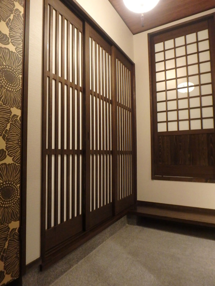 TDホーム静岡西 ウエストンホームズ【和風、自然素材、省エネ】玄関に入ると見える、ホールへと続く三枚格子戸。右手の敷台から続く片引きの格子戸は、リビングひとつながりの畳スペースへとつながっており、急な来客にも対応可能できる