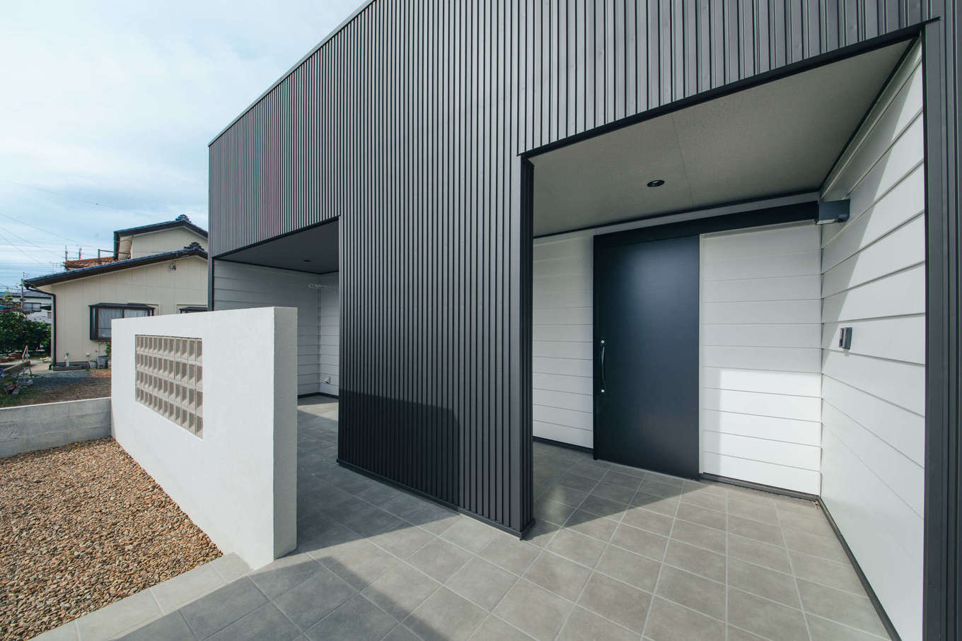 DAITOKU（大得工務店）【デザイン住宅、子育て、間取り】コートハウスのように外部からの視線を遮断。玄関まわりのアクセントに白のガルバリウムを段葺きで施工した