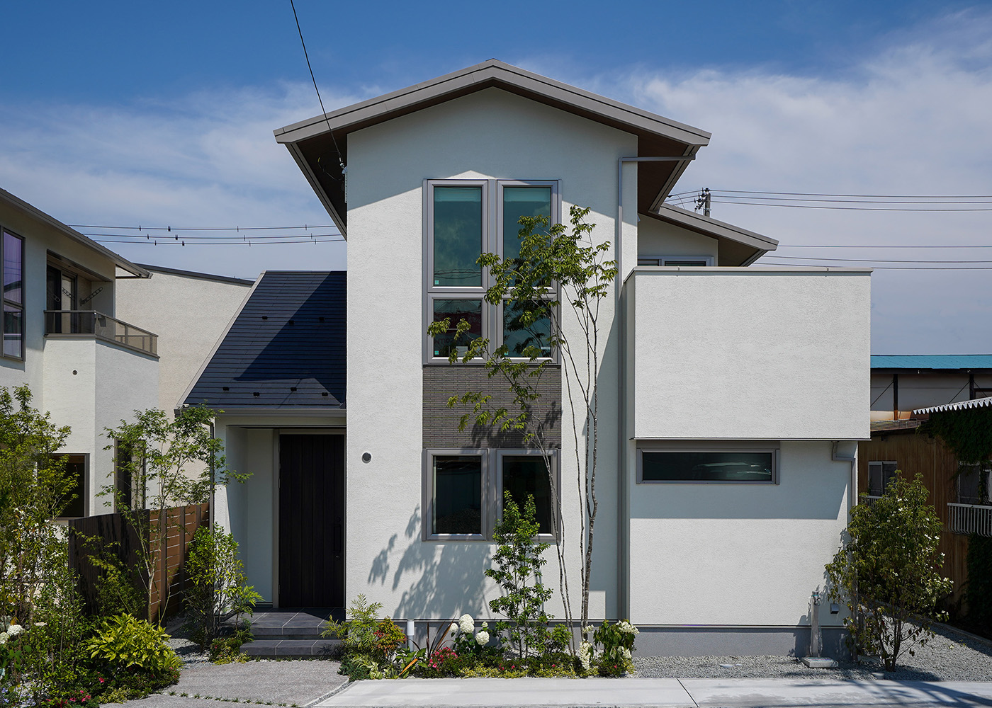 ミサワホーム甲信【デザイン住宅、収納力、間取り】正面切妻が印象的な外観を、塗り壁とタイルでコーディネート。中央2階にはLDKと、その右側にバルコニーを設けた