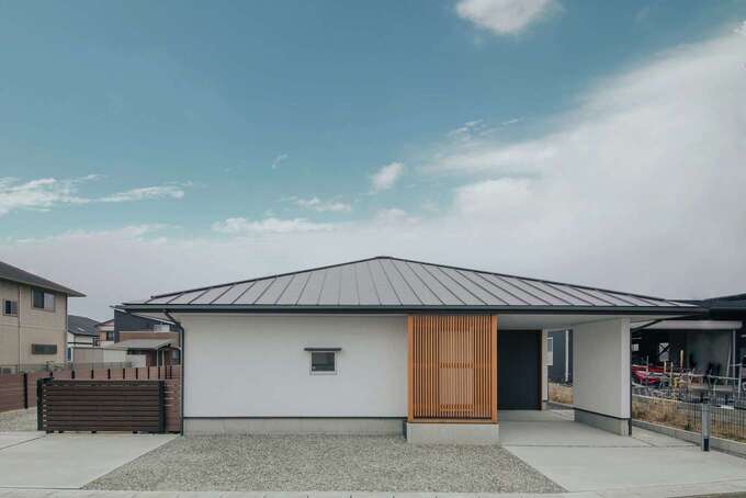 ビルトインガレージ付きの平屋の外観。方形屋根のラインが美しく上品な佇まい。玄関の目隠しに設けた洗柿（あらいがき）色の格子がアクセントとなっている