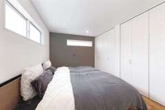 8畳の主寝室。キッチン、トイレに合わせてグレーのアクセントクロスを採用。大容量の壁面収納は奥さまの衣類をすべてしまっても余裕たっぷり