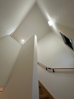 白を基調としたシンプルなデザインの階段。明るい照明が空間を広く見せ、手すりが安全性を確保している。住宅内のアクセントとしても機能している。