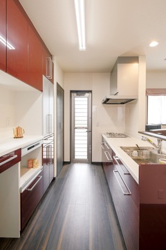 家族に背を向けて孤独感の強かったキッチン。奥さまがTVや景色を見ながら料理できるよう、対面式を採用。 赤い食器棚が空間の差し色になっている