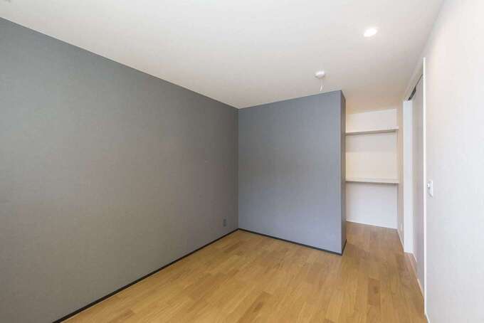 白壁にグレーのアクセントクロスが目をひく寝室。モノトーンの配色が心地よい落ち着きを生みだしている