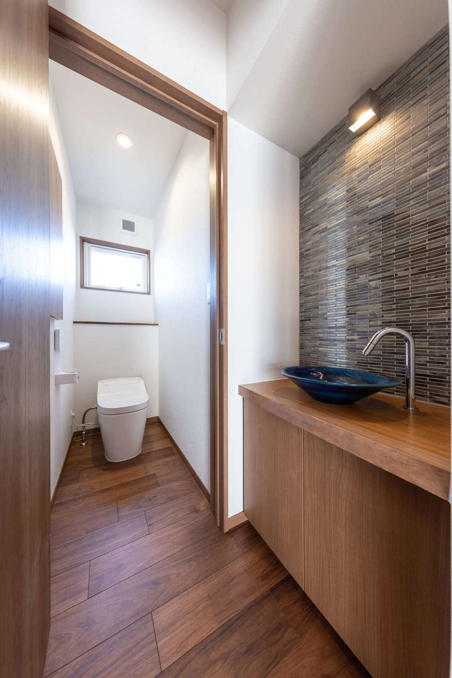 渡辺建設【デザイン住宅、夫婦で暮らす、平屋】手洗い専用の洗面台。ご主人が見つけて購入した陶器のボウルが映えるよう、壁にタイルを貼り、一枚板の収納棚を造作した