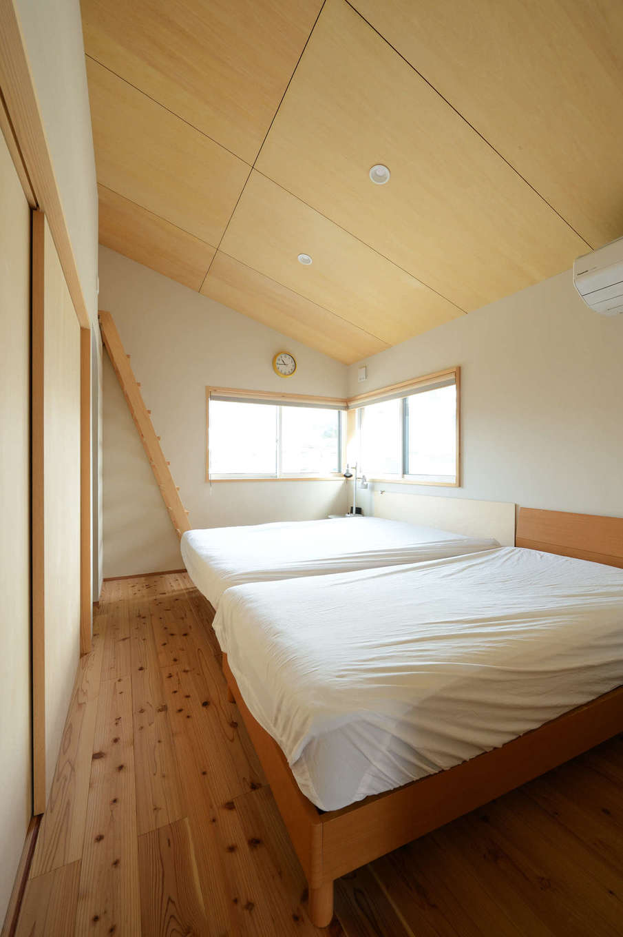 石牧建築【自然素材、狭小住宅、建築家】窓からアクトタワーが見える主寝室。奥にご主人の隠れ家的書斎もつくった。床は天竜杉を使い、1階と変化をつけて。建て坪が小さい分、収納不足を考慮して2階の各部屋にロフトを確保