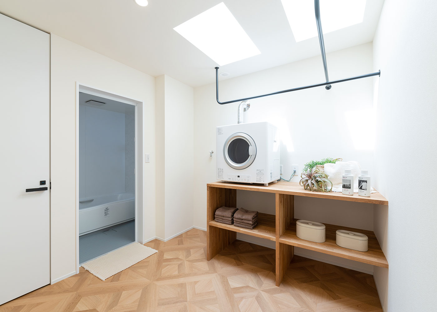 住家 JYUKA【デザイン住宅、間取り、建築家】浴室＆ランドリールームは2階にレイアウト。トップライトから明るさが降り注ぎ、家事の時間も気持ちよく過ごせる。ガス乾燥機の採用により、洗濯はこのスペースで完結。共働きのM夫妻にとって、家事のしやすさも大切なポイントだった